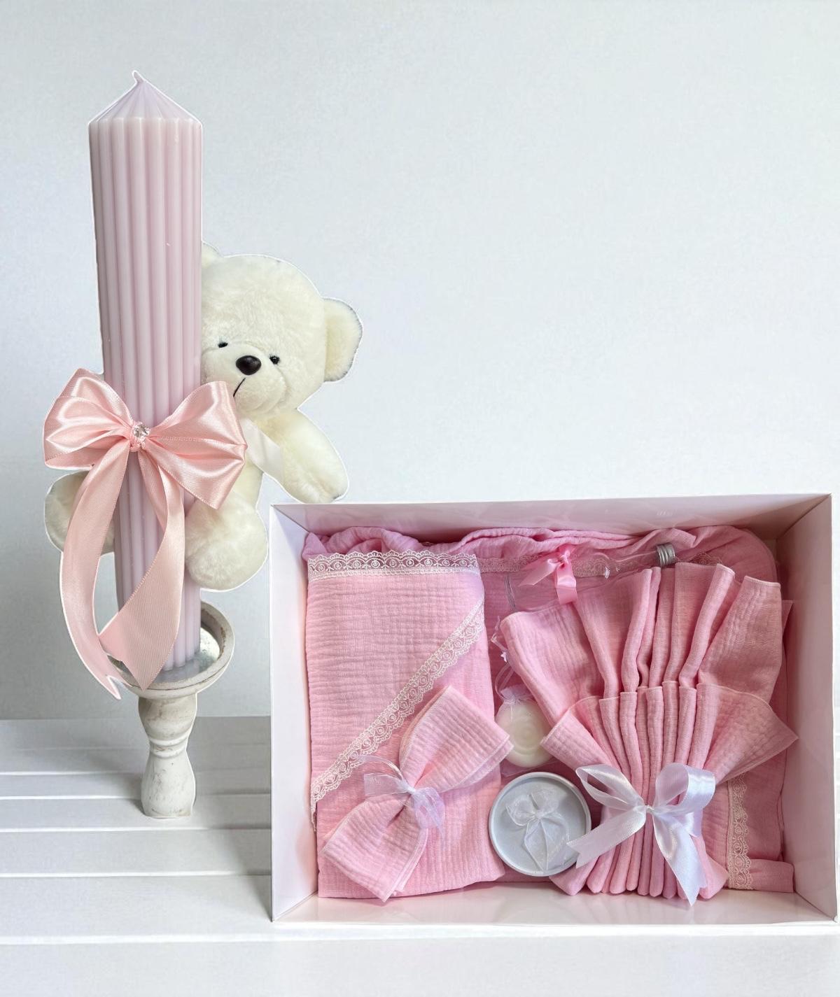 Trusou de botez cu un ursuleț alb și accesorii roz, inclusiv o lumânare și textile.